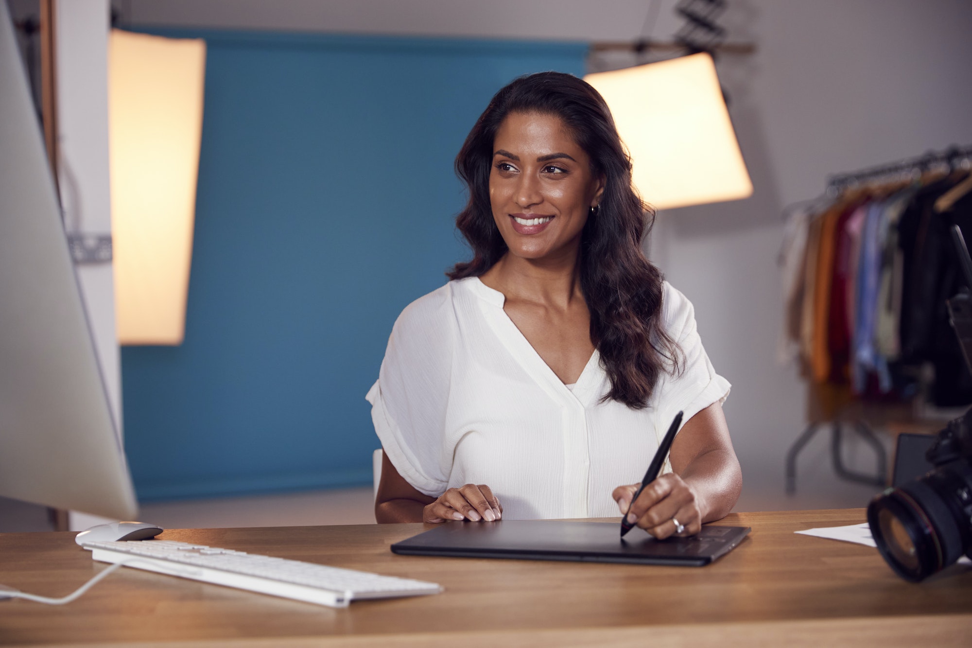 Female Photographer Designer Or Retoucher At Desk Working On Images On Computer In Studio