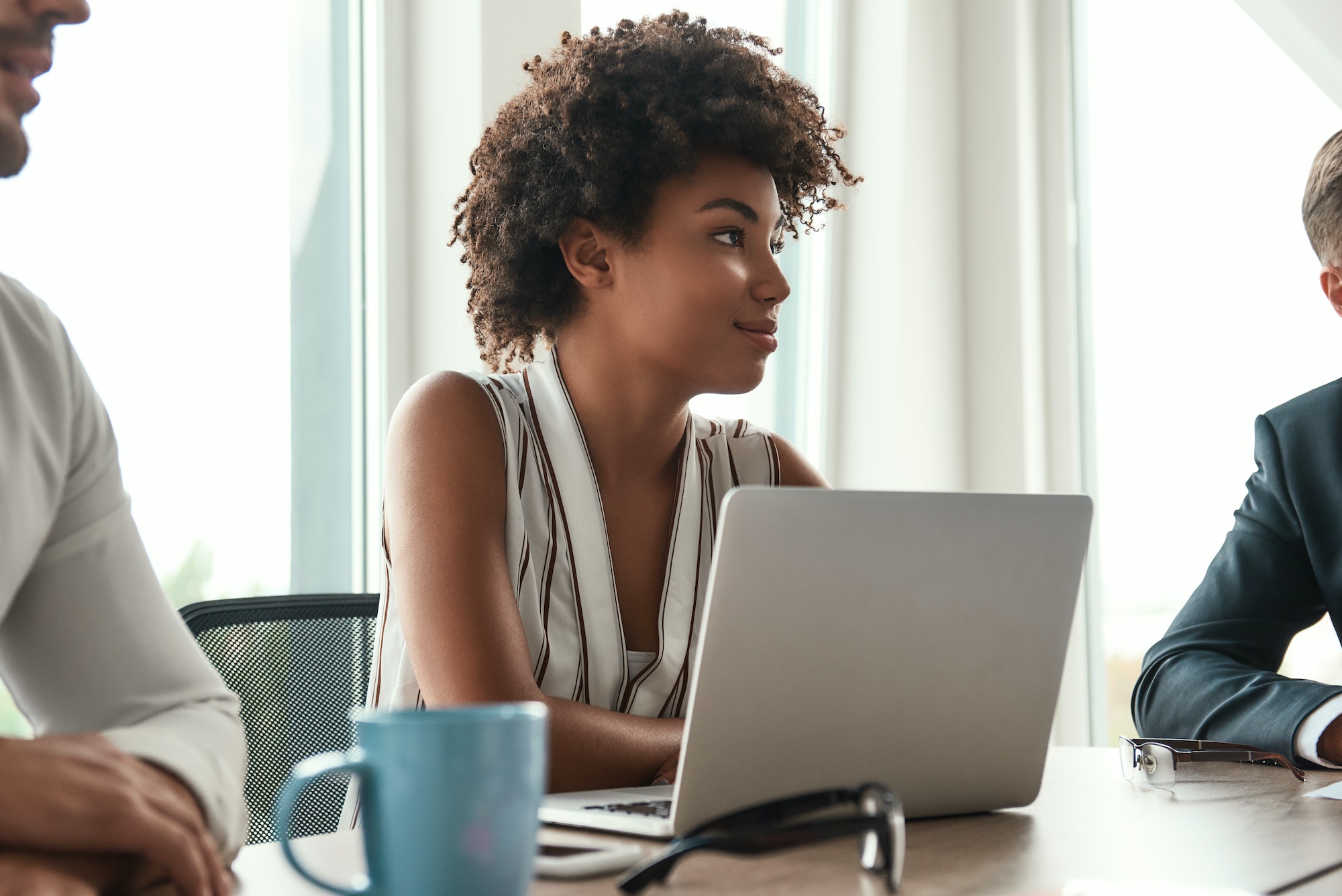 She loves her work. Beautiful african woman sitting at business meeting and smiling